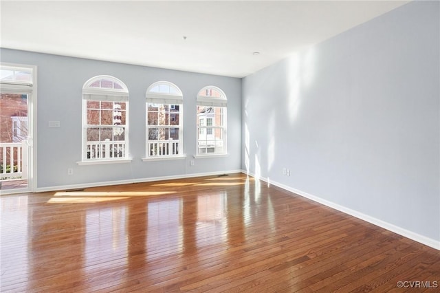 spare room with hardwood / wood-style floors and baseboards