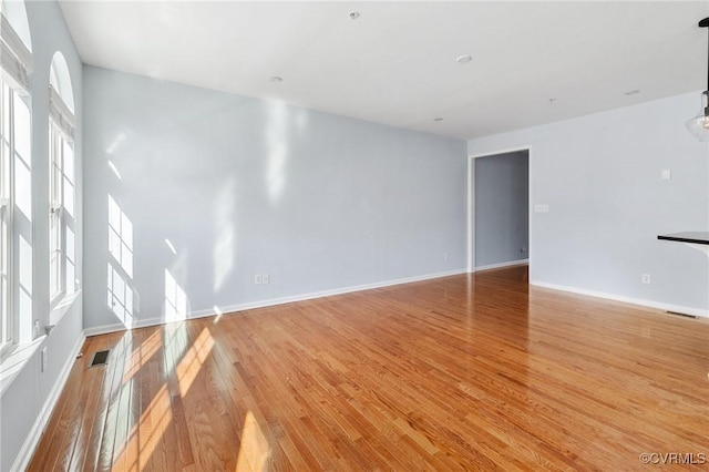 unfurnished living room featuring light wood finished floors, visible vents, and baseboards