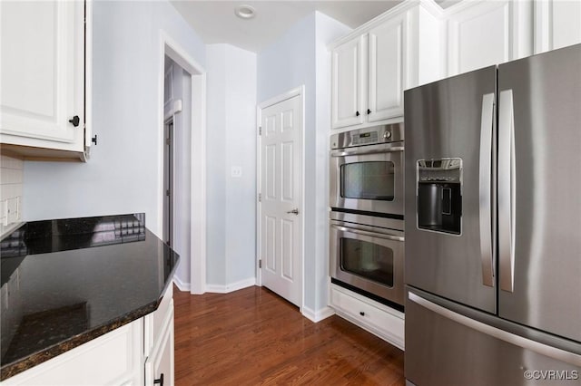 kitchen featuring stainless steel appliances, tasteful backsplash, dark wood-style floors, and white cabinetry