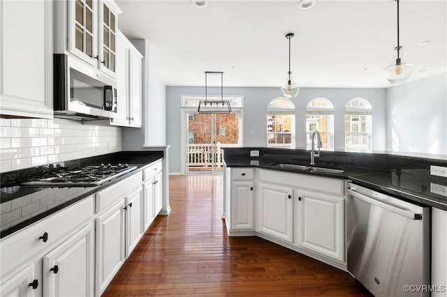 kitchen with a sink, plenty of natural light, tasteful backsplash, dark wood-style floors, and stainless steel appliances