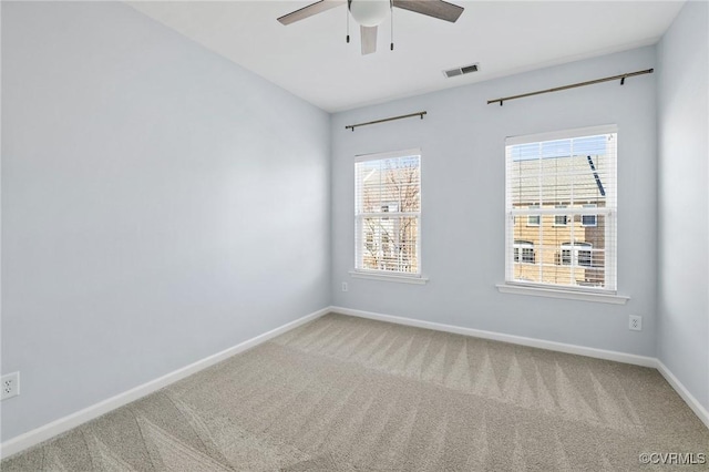 empty room featuring visible vents, carpet floors, baseboards, and ceiling fan