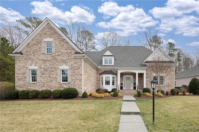 traditional-style house with a front lawn, brick siding, and a shingled roof