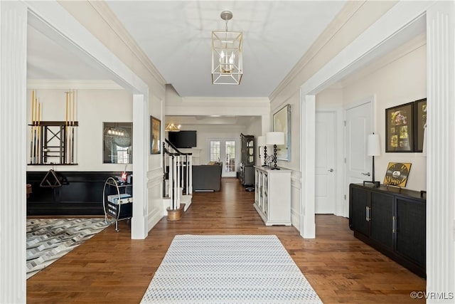 foyer entrance featuring dark wood finished floors, a chandelier, crown molding, and stairs