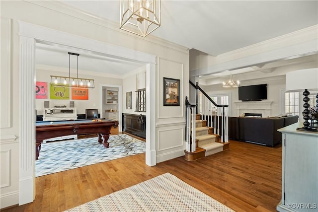 office space with wood finished floors, coffered ceiling, a fireplace, ornamental molding, and a notable chandelier