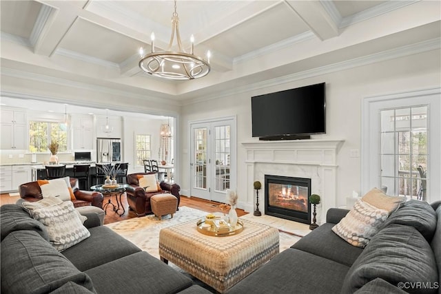 living area with a chandelier, beam ceiling, light wood-style flooring, and a fireplace