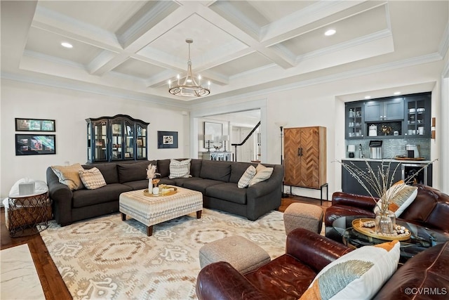 living room featuring wood finished floors, coffered ceiling, beam ceiling, ornamental molding, and a notable chandelier