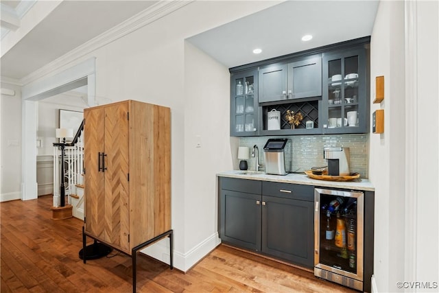 bar with backsplash, crown molding, bar area, beverage cooler, and a sink