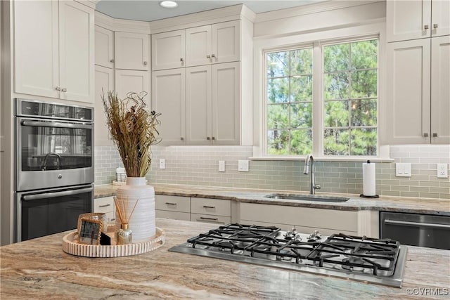 kitchen featuring a sink, stainless steel appliances, light stone counters, and tasteful backsplash