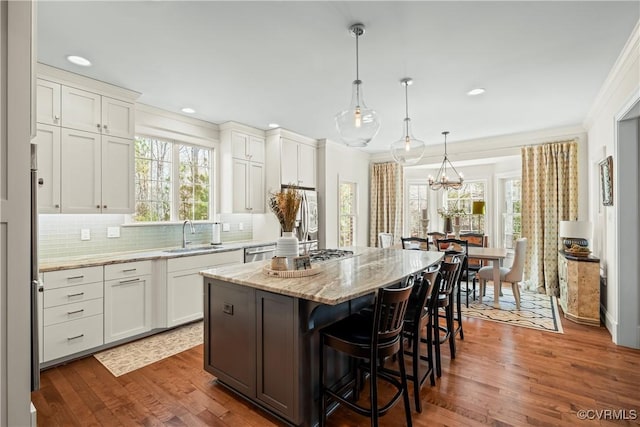 kitchen with a breakfast bar, a sink, a center island, stainless steel appliances, and decorative backsplash