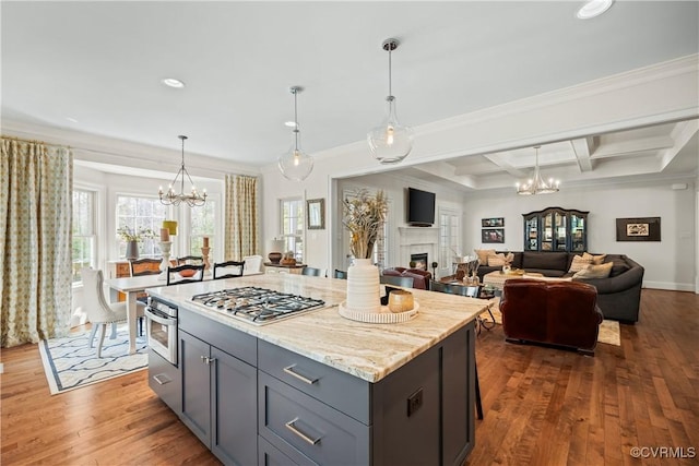 kitchen with a chandelier, a tiled fireplace, coffered ceiling, and wood finished floors