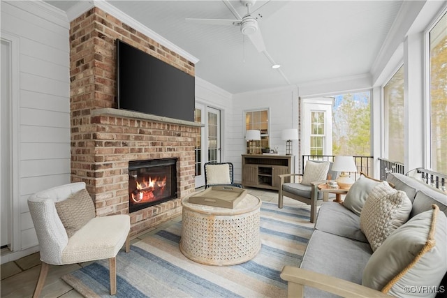 living area with a fireplace, crown molding, and ceiling fan