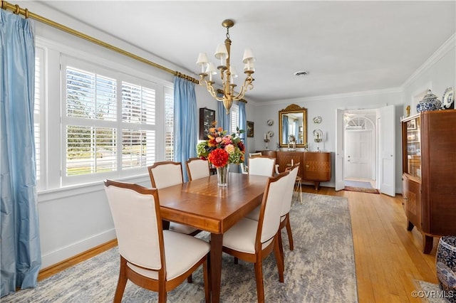 dining space with baseboards, visible vents, an inviting chandelier, light wood-style flooring, and ornamental molding