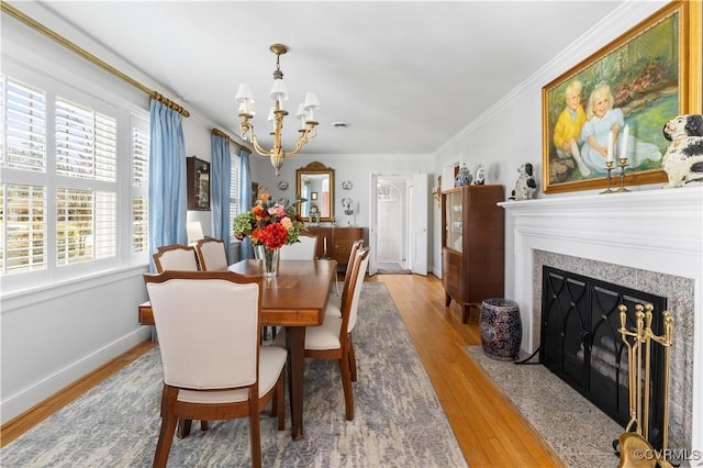 dining area with wood finished floors, an inviting chandelier, crown molding, a premium fireplace, and baseboards