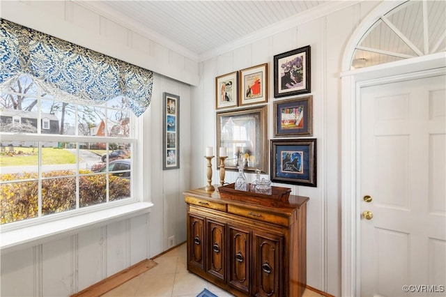 interior space with ornamental molding, light tile patterned flooring, and a decorative wall