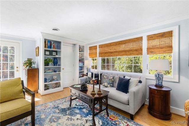 living area featuring wood finished floors, crown molding, and a healthy amount of sunlight