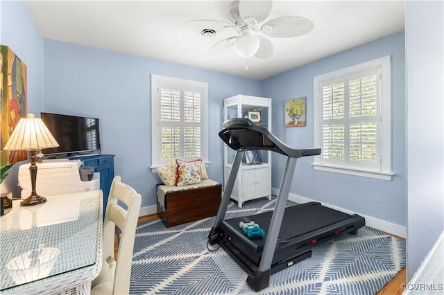 exercise area featuring visible vents, baseboards, and ceiling fan