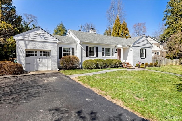 ranch-style house with fence, a front yard, an attached garage, brick siding, and a chimney