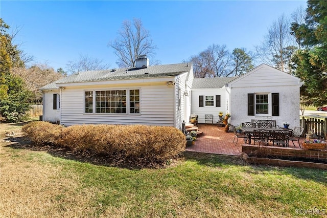 back of property with entry steps, a chimney, a yard, and a patio