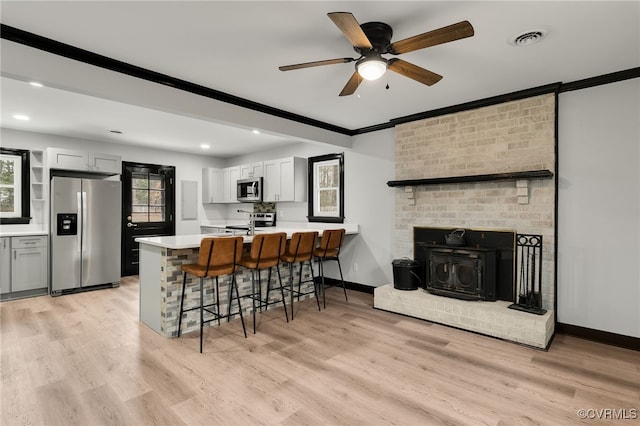 kitchen featuring visible vents, a breakfast bar area, a peninsula, stainless steel appliances, and crown molding