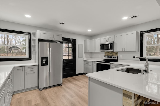 kitchen with visible vents, a healthy amount of sunlight, appliances with stainless steel finishes, light wood-type flooring, and a sink