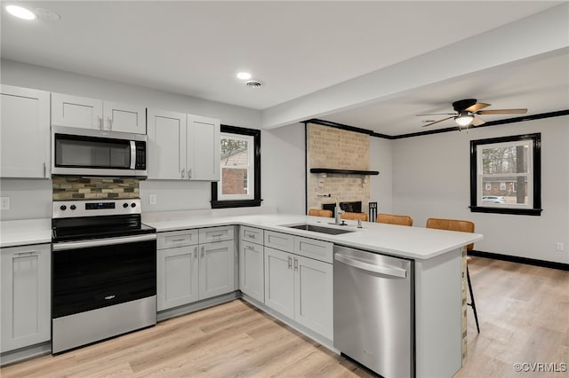 kitchen featuring stainless steel appliances, a peninsula, and light countertops