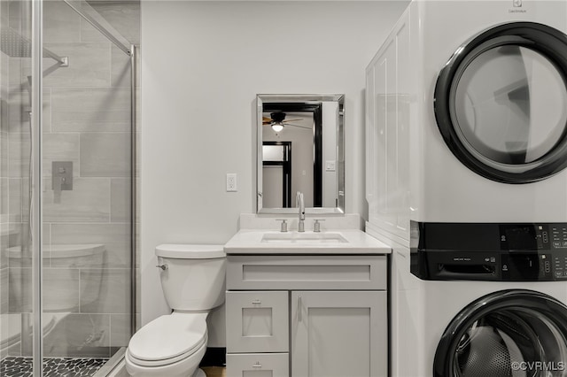 bathroom with toilet, stacked washer and dryer, a shower stall, and vanity