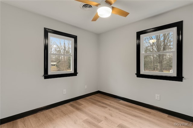 empty room featuring baseboards, light wood-style floors, visible vents, and a healthy amount of sunlight