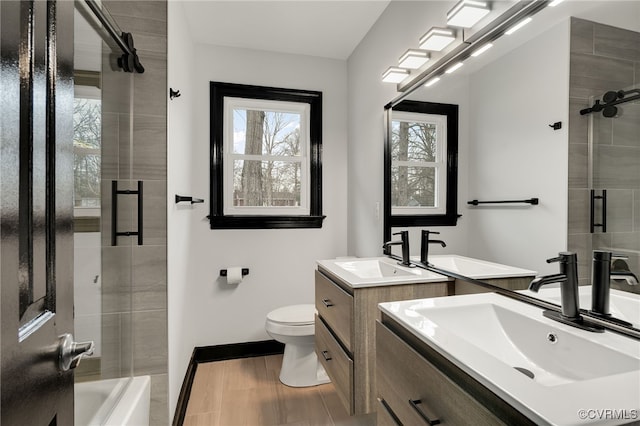 bathroom featuring baseboards, two vanities, a sink, and toilet