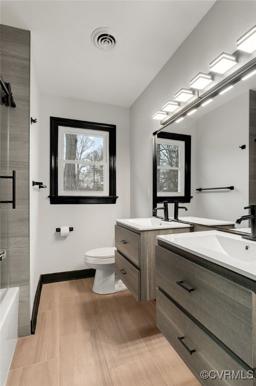 full bathroom with toilet, a sink, visible vents, baseboards, and double vanity