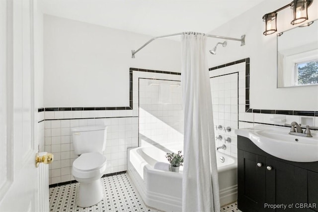 full bath featuring toilet, shower / bath combo, vanity, and tile walls