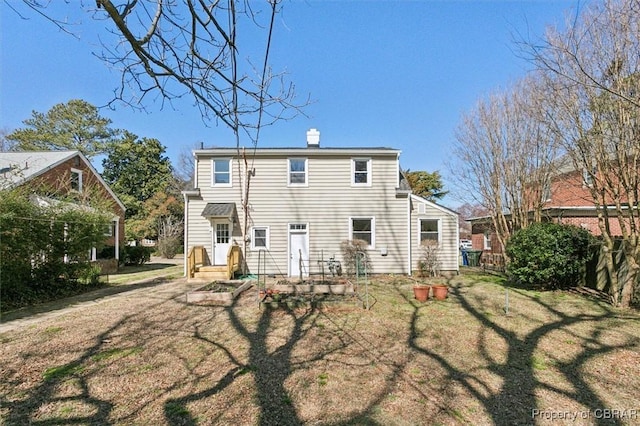 rear view of property with a lawn and a chimney