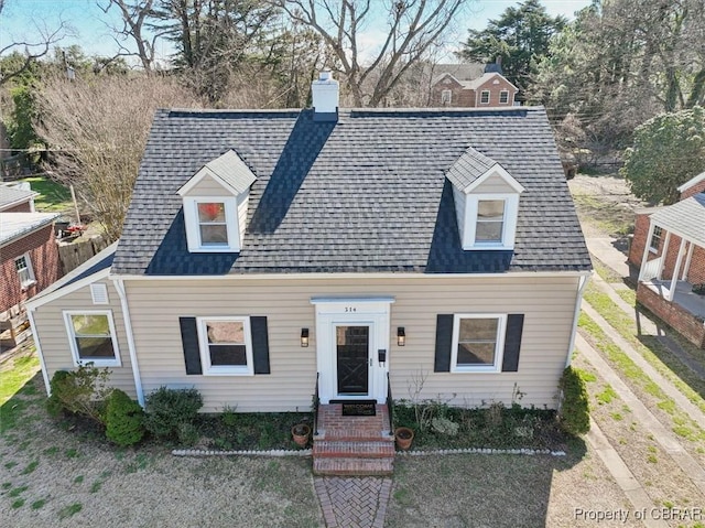 cape cod house featuring roof with shingles and a chimney