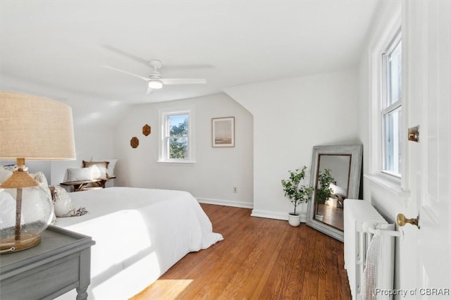 bedroom with baseboards, lofted ceiling, radiator heating unit, ceiling fan, and light wood-style floors