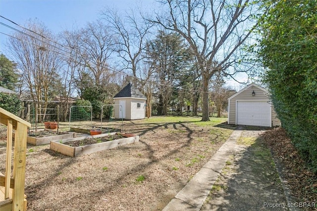 view of yard featuring an outbuilding, a garden, driveway, and a detached garage