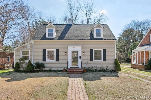 cape cod house featuring a chimney, a front lawn, and roof with shingles