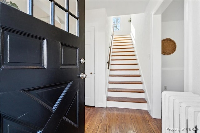 entrance foyer featuring radiator, stairs, and wood finished floors