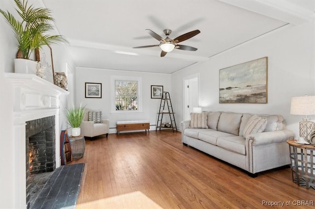 living room with ceiling fan, hardwood / wood-style floors, a baseboard radiator, and a fireplace with flush hearth