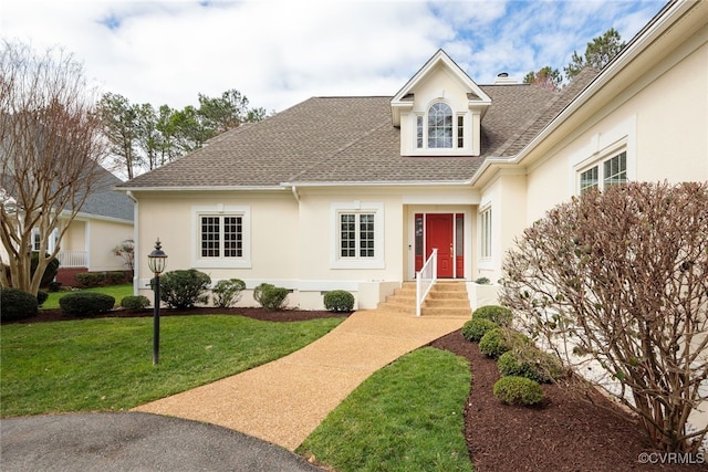 view of front of house with roof with shingles, a chimney, a front lawn, and stucco siding