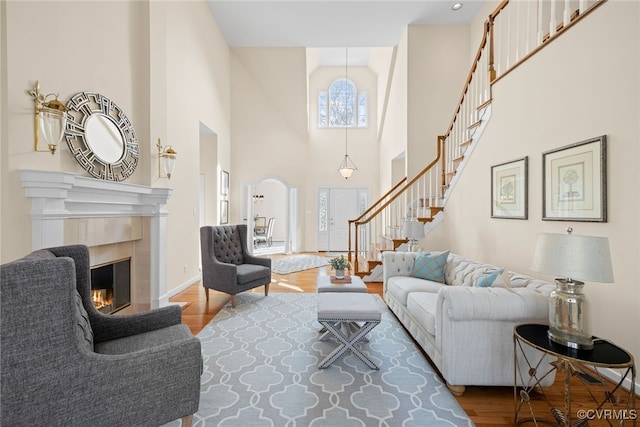 living room with baseboards, a tile fireplace, wood finished floors, a high ceiling, and stairs