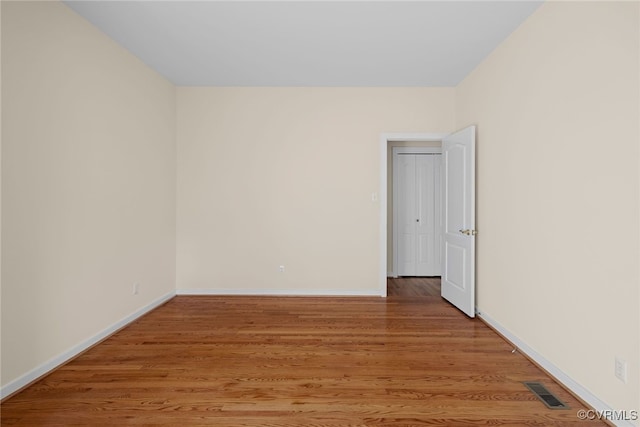 empty room featuring baseboards, visible vents, and light wood finished floors