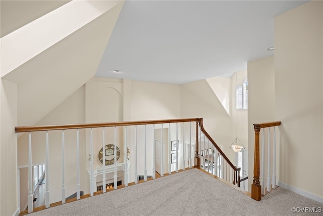 corridor with carpet floors, vaulted ceiling, and an upstairs landing