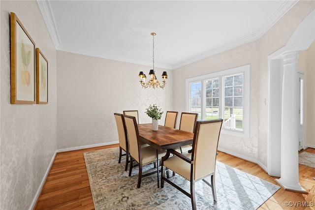 dining room featuring decorative columns, ornamental molding, wood finished floors, a chandelier, and baseboards