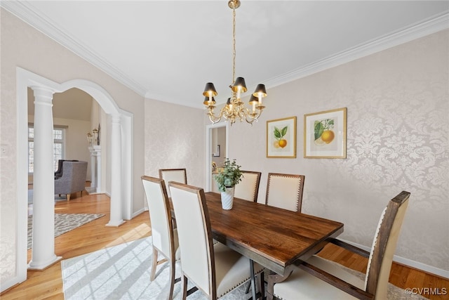 dining space with light wood-type flooring, decorative columns, arched walkways, and crown molding