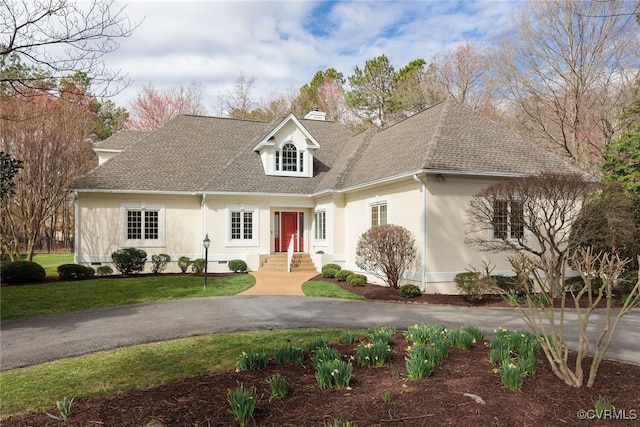 cape cod-style house with driveway, a shingled roof, a chimney, and stucco siding