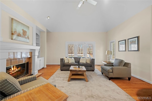 living room featuring light wood finished floors, baseboards, a fireplace, and built in features