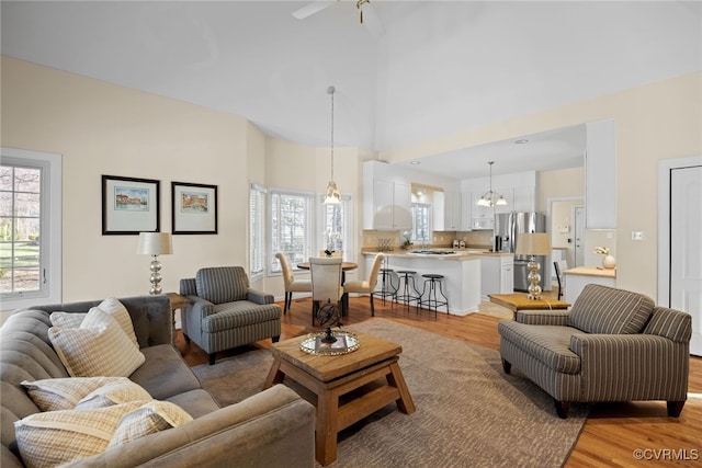 living area with a high ceiling, light wood finished floors, and an inviting chandelier