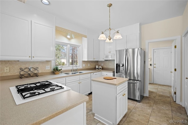 kitchen featuring white appliances, tasteful backsplash, white cabinets, light countertops, and a sink