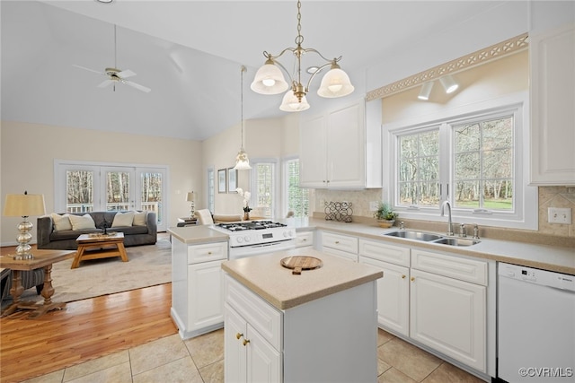 kitchen with white appliances, a sink, open floor plan, light countertops, and tasteful backsplash