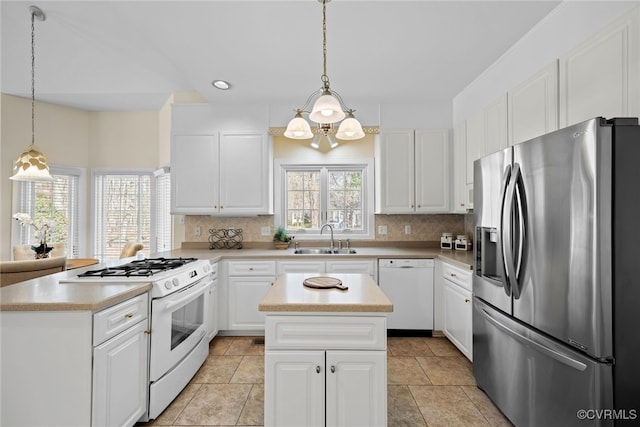 kitchen with a peninsula, white appliances, backsplash, and a sink