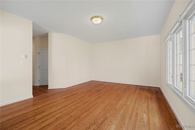 spare room with light wood-style floors, visible vents, and baseboards